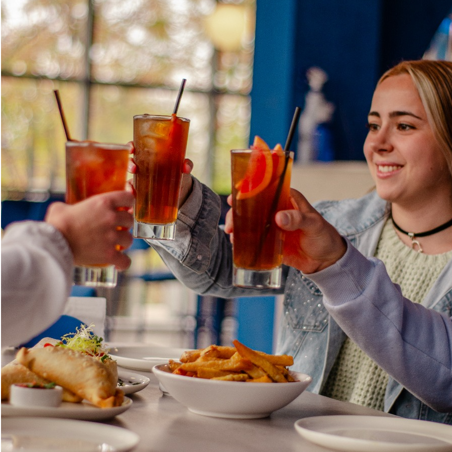 Amigos compartiendo bebidas y platos en una mesa de Bruttal